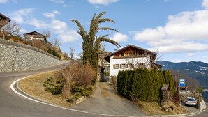A winding road leading to a house with a stone wall on one side and a mountain backdrop. - Holiday Apartment “Rafaser - Albina” with Mountain View & Wi-Fi (Feldthurns)