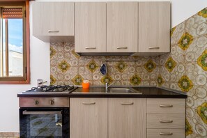 A kitchen with a gas stove, sink, and wooden cabinets.