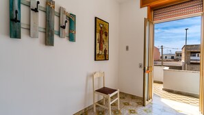 A room with a chair, a wooden wall-mounted rack, and a painting. - Apartment near the sea - Appartamento Torre Lapillo (torre lapillo)