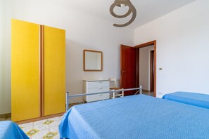 A bedroom with a bed, a wardrobe, a desk, and a door.