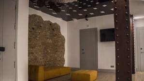 A room with a brick wall, a grey door, and a brown metal structure. - Hostal Juliette & Coworking (Madrid)