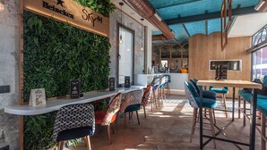 A restaurant interior with a wooden bar, green wall decor, and a blue ceiling. - Hostal Juliette & Coworking (Madrid)