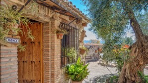 Un bâtiment rustique avec une porte en bois, une enseigne indiquant « DONA » et des plantes en pot.
