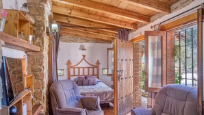 Une chambre rustique avec un plafond en bois, un mur en pierre, un lit avec des oreillers et une chaise.