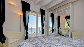 Un dormitorio con una cama grande, dos sillones, un sofá y un balcón con vistas.