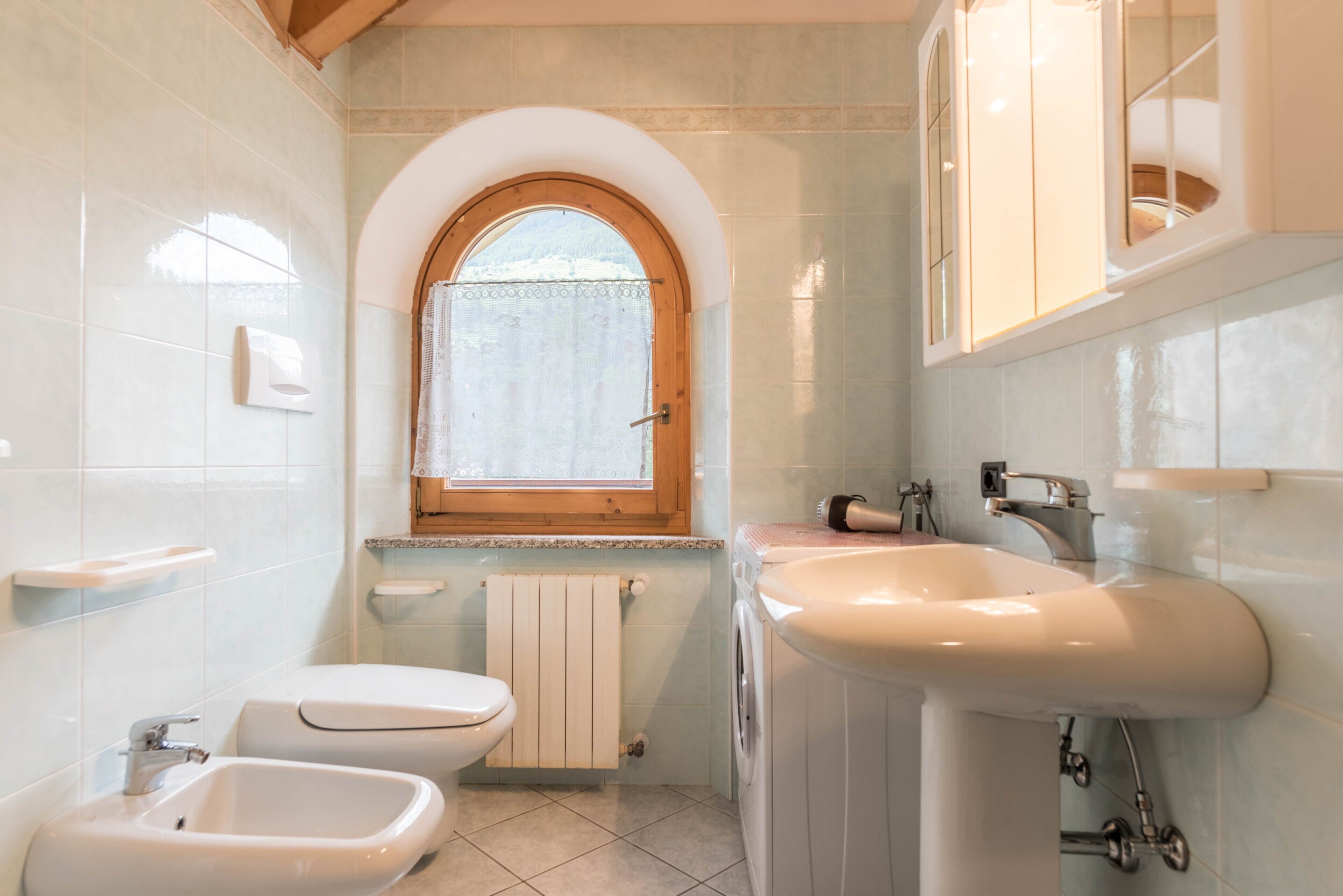 Ein Badezimmer mit Toilette, Bidet, Waschbecken und einem Fenster mit Aussicht.