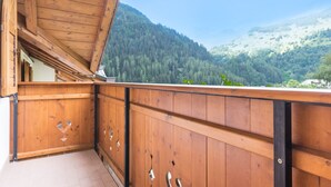 A wooden balcony with a view of a forested mountain. - Holiday Apartment "Bamby - Vioz" with Balcony, Garden & Mountain View (Cogolo di Pejo)