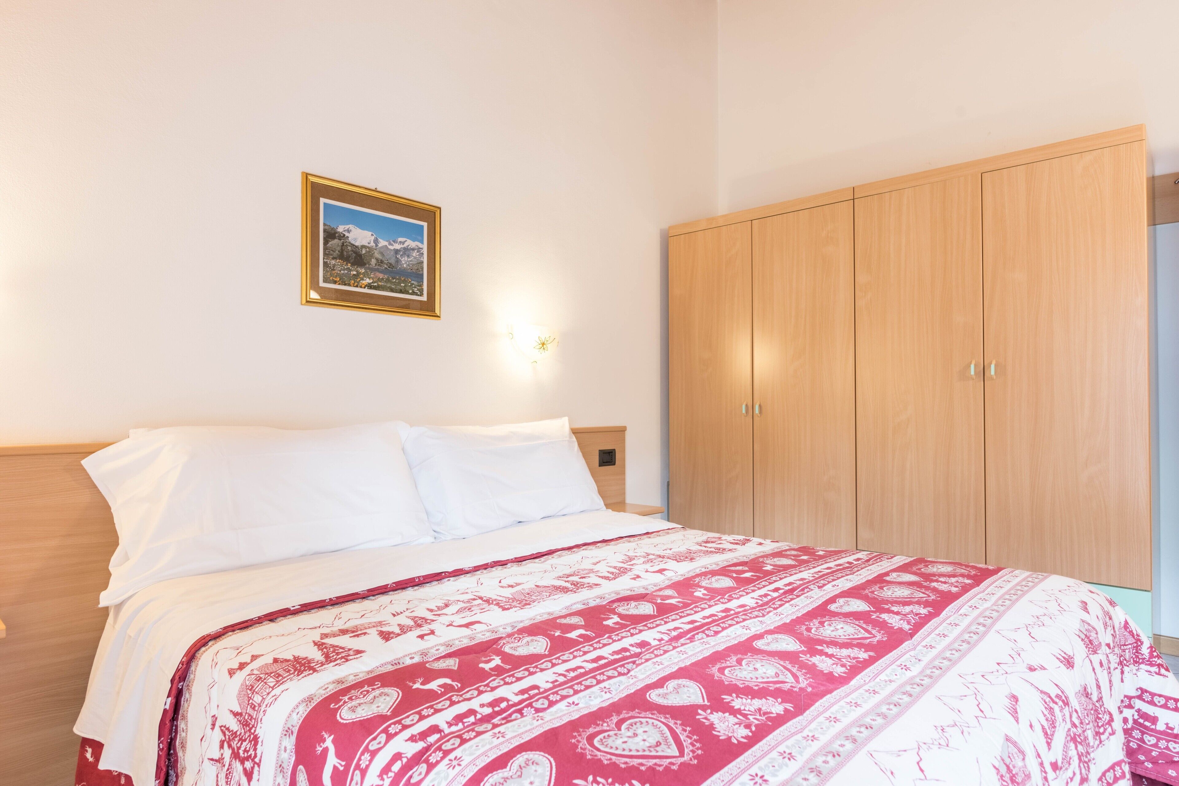 Une chambre à coucher avec un lit, une armoire en bois, un tableau accroché au mur et une lampe de chevet.
