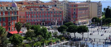 A public square with fountains, surrounded by historic buildings with red and yellow facades.