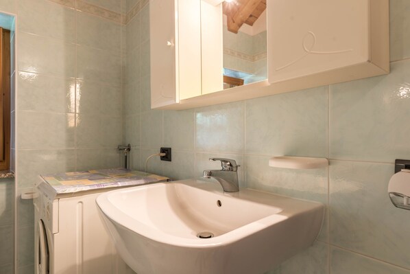 A bathroom with a sink, mirror, and tiled walls.