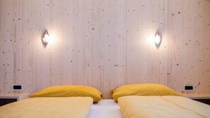 A room with two beds, wooden walls, and wall-mounted lights. - Idyllic Apartment "Kronplatz" with Balcony, Garden and Wi-Fi (San Martino in Badia)