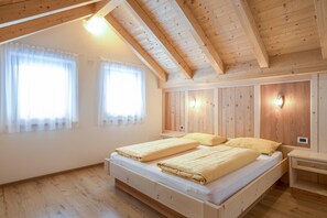 Une chambre avec un plafond en bois, un lit avec deux oreillers, une table de chevet et une lampe fixée au mur.