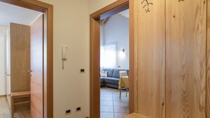 A hallway with wooden doors, a bench, and a living area with a sofa and table. - Idyllic Apartment "Kronplatz" with Balcony, Garden and Wi-Fi (San Martino in Badia)