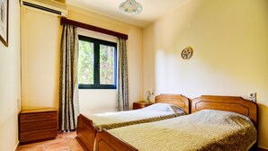 Ein Schlafzimmer mit zwei Holzbett, einem Fenster mit Vorhängen, einem Nachttisch und einer Wandleuchte.