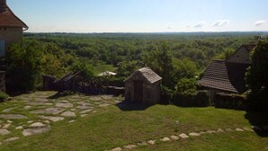 Un paysage rural avec des sentiers de pierre, un petit bâtiment en pierre et une vue sur une zone boisée.