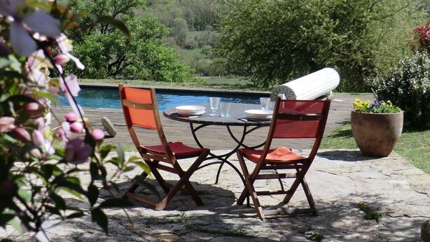 Un espace extérieur aménagé pour les repas, avec une piscine, entouré de verdure et de collines.