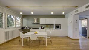 Una cocina moderna con armarios blancos, una mesa de comedor con sillas y un horno empotrado.