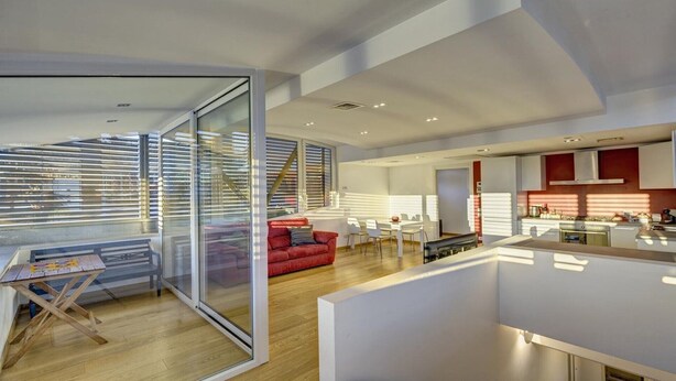 Un interior moderno con zona de comedor, cocina y un sofá rojo.