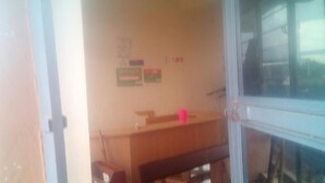 A classroom with a wooden desk, a pink cup, and educational posters on the wall.