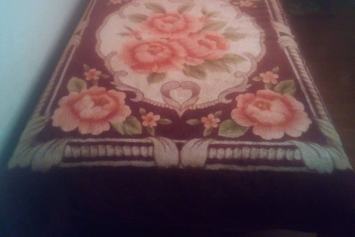 Ein Bett mit floralem Überwurf, einem Holzkopfschild und einem Kissen.