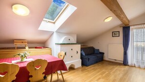 Ein Zimmer mit Esstisch, Stühlen, einer Couch, einem Fenster mit Blick und einer Decke mit Holzbalken.