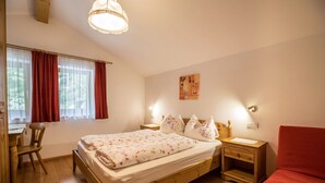 Ein Schlafzimmer mit einem hölzernen Bett, einem Schreibtisch, einem Stuhl und einem roten Sessel.