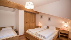 Ein Schlafzimmer mit einem hölzernen Bett, einem Holzschrank, einem Nachttisch und einer Pendelleuchte.