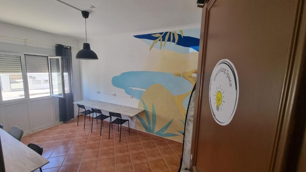 Ruokailutila, jossa on pöytä ja tuolit, seinämaalaus ja ovi, jossa on tarra.