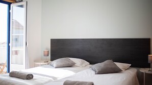 Een hotelkamer met twee bedden, een groot donker hoofdeinde en uitzicht naar buiten.