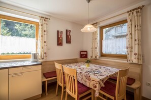 Ein Essbereich mit Tisch, Stühlen, einer Hängeleuchte und einem Fenster mit Vorhängen.