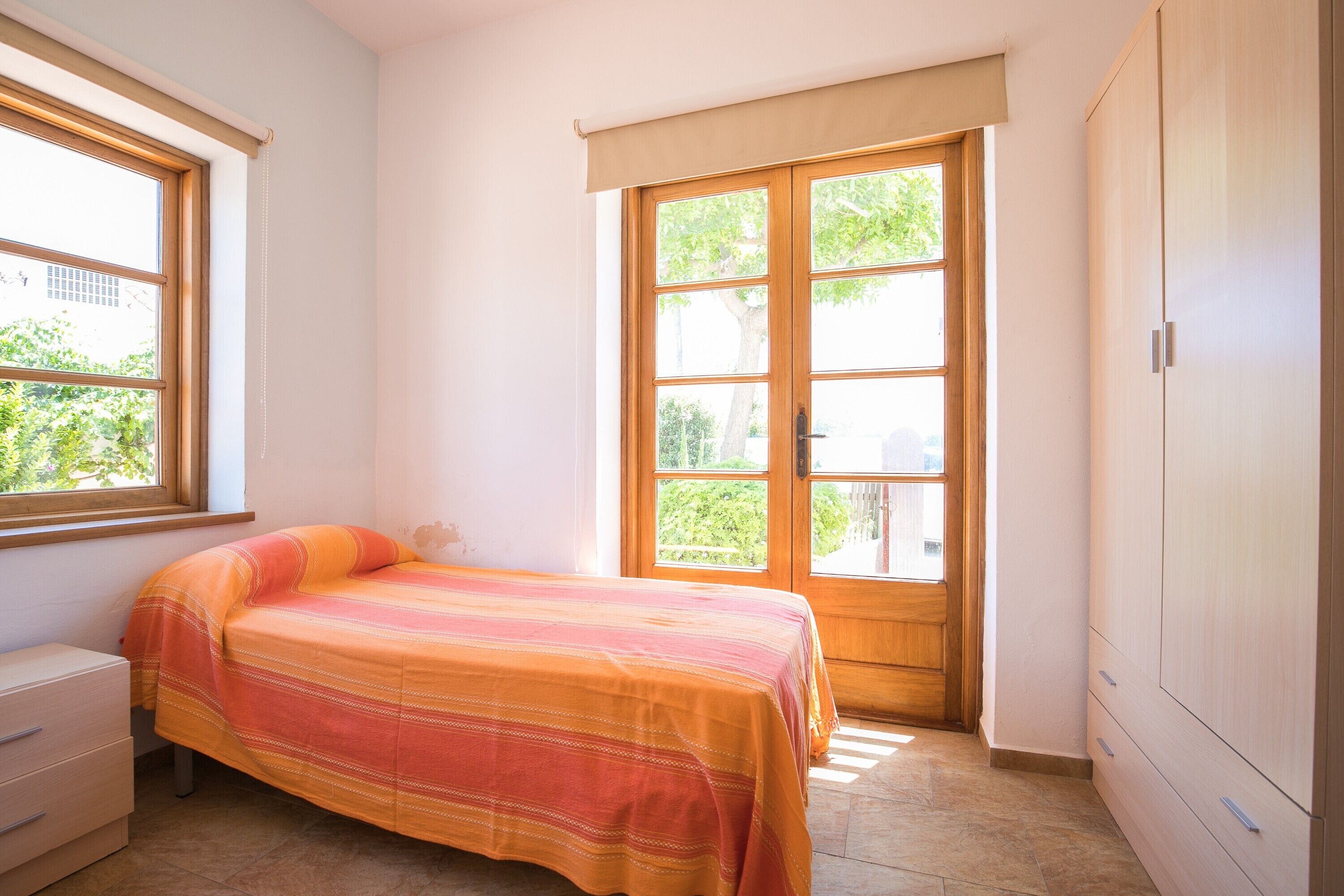 Un dormitorio con cama, ventana y armario.