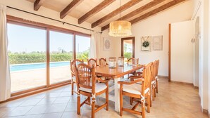 Un espace repas avec une grande table, des chaises en bois et une vue sur une piscine.