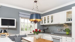 A modern kitchen with white cabinetry, a wooden dining table, and a large window. - Uhlenhof E from A&M - Uhlenhof E (Kampen (Sylt))