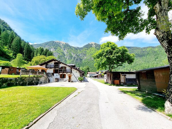 Un village rural avec des maisons traditionnelles en bois, une route pavée et des montagnes en arrière-plan.