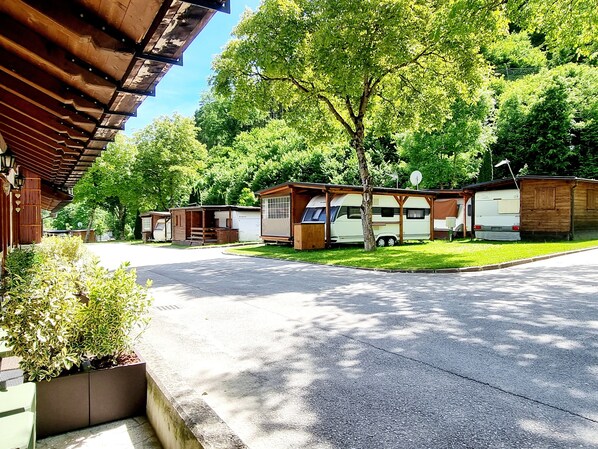 A caravan park with multiple caravans, a paved driveway, and a building with a wooden facade.