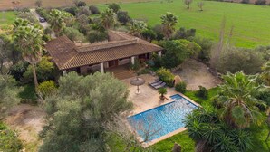 Een villa met zwembad, omgeven door weelderige begroeiing en velden.