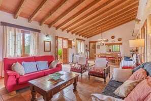 Un salon spacieux avec un canapé rouge, des fauteuils à motifs et une table basse en bois.