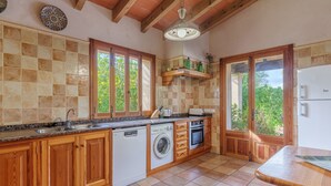 Een keuken met houten kastjes, een wasmachine, een oven en een koelkast.