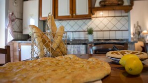 A kitchen with a wooden table, a basket of bread, and a lemon on the counter.