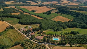 An aerial view of a rural property with fields, a swimming pool, and a small cluster of buildings.
