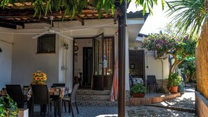 Eine Außenpatio mit Tisch und Stühlen, einem überdachten Sitzbereich und Kübelpflanzen.