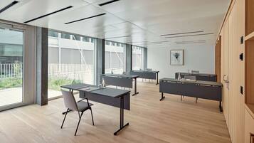 Une salle de conférence moderne dotée de grandes fenêtres, d’un plancher en bois et d’un mobilier aux lignes épurées.