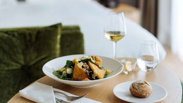 Une table à manger avec une assiette de nourriture, un verre de vin blanc et une petite assiette contenant une pâtisserie.