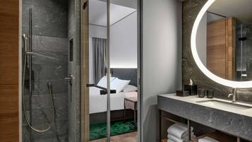 Un baño moderno con cabina de ducha de vidrio, un espejo grande y tocador con lavabo y espacio para toallas.