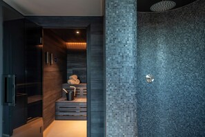 A modern bathroom with a dark wood vanity, a glass shower enclosure, and a mosaic tile wall. - Hyatt Regency Zurich Airport The Circle (Kloten)