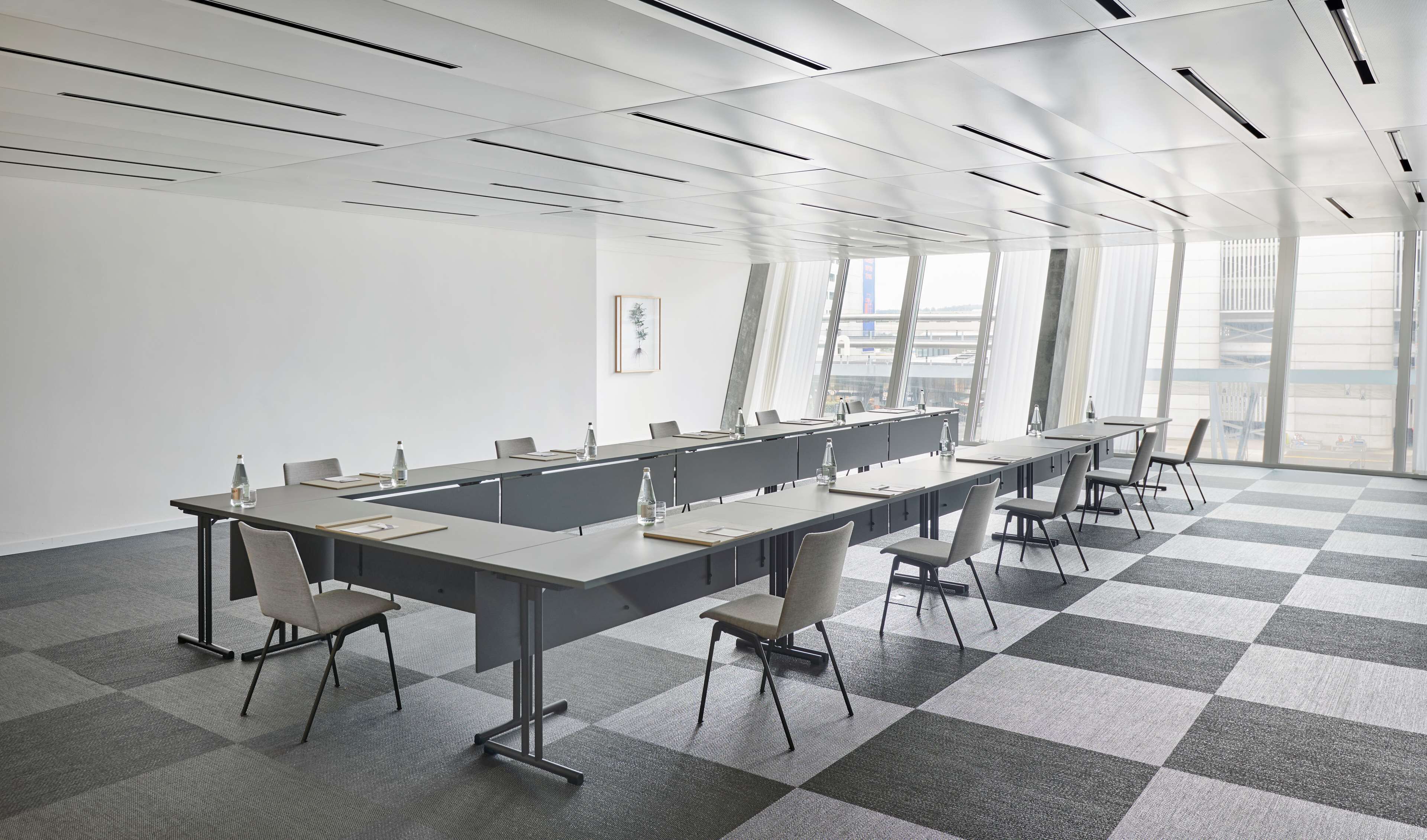 Un salón de conferencias con una larga mesa, sillas y un piso a cuadros.