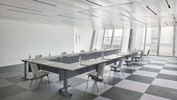 Un salón de conferencias con una larga mesa, sillas y un piso a cuadros.