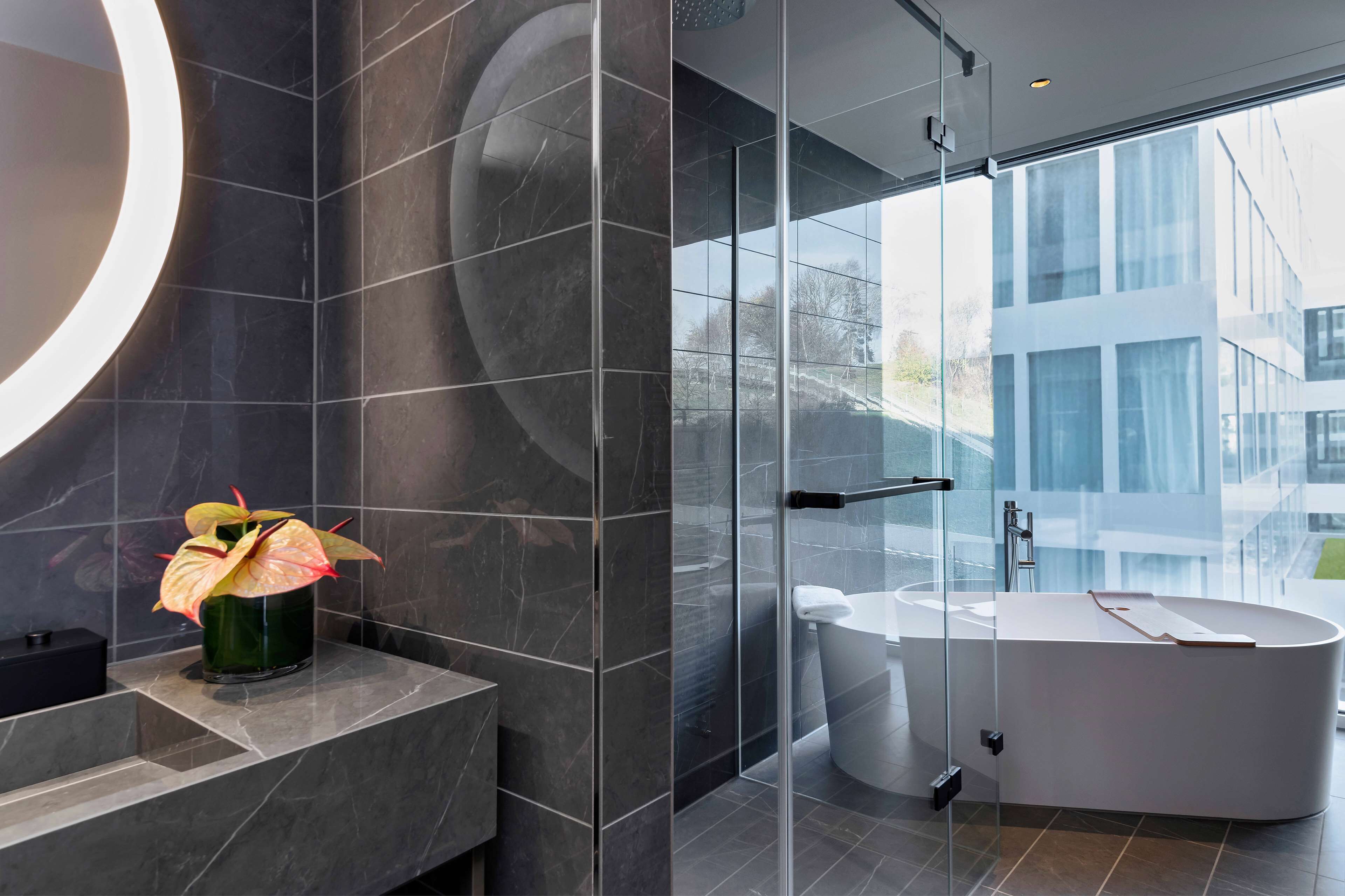 Une salle de bain moderne avec une baignoire sur pieds, une douche à parois de verre et un grand miroir.