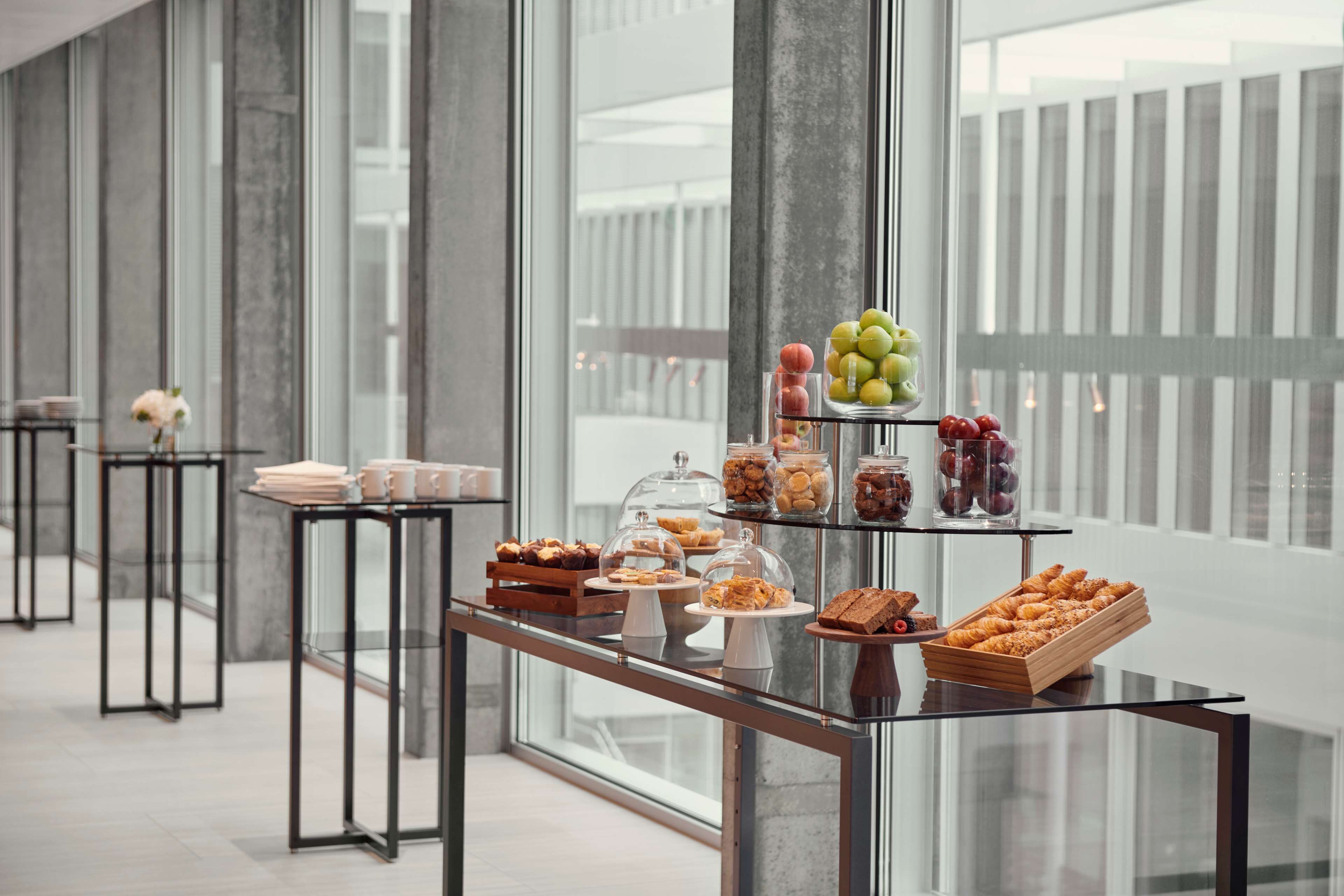 A modern hotel corridor with glass display cases filled with pastries and fruits.