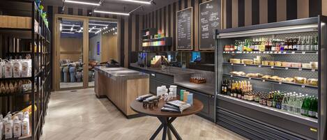 A modern coffee shop interior with a counter, shelves of coffee beans, and a display of bottled beverages.